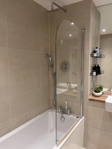 a bathroom with a shower with a tub and a sink at Lovely Charming 2-Bedroom Apartment in Bow London in London
