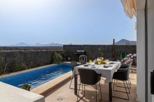 a dining table and chairs next to a swimming pool at Villa LanzaCosta Golf in Teguise