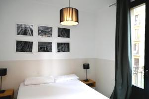 - une chambre avec un lit blanc et des photos sur le mur dans l'établissement Homenfun Barcelona Sagrada Familia Marina, à Barcelone