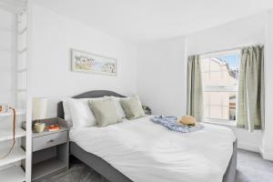 una camera da letto con un letto con lenzuola bianche e una finestra di The Cottage, Budleigh Salterton a Budleigh Salterton