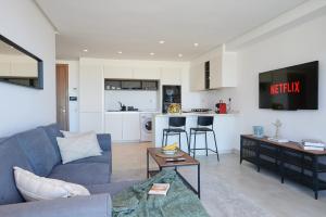 a living room with a blue couch and a kitchen at Apartment Sea View B2 - Mosquée Hassan II - By TheCasaEdition in Casablanca