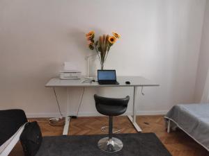 een bureau met een laptop en een vaas met bloemen erop bij Downtown 3 BDR Charm - walk to all attractions in Bratislava