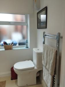 Baño con aseo, ventana y toalla en Offa Hideaway en Leamington Spa
