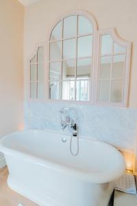 een badkamer met een wit bad en een spiegel bij The Fuzzy Duck in Newbold on Stour