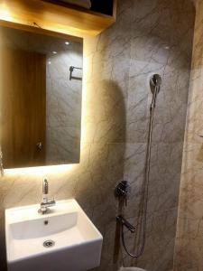 Un baño con lavabo y ducha con espejo. en Hilarity Inn, en Padappai