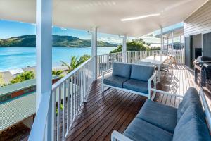 a porch with a couch and chairs and the ocean at Casuarina Cove 14 & Buggy - Hamilton Island in Hamilton Island