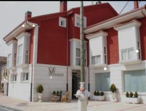 a woman standing in front of a red and white building at hotel asador versus in Burgos