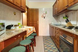 una cocina con armarios de madera y taburetes verdes acolchados en Palheiro Residence Familiar 1, en Funchal 11 fotos más