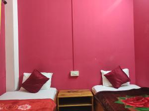 Dirang DzongにあるHotel Zambalaのピンクの壁の客室で、ベッド2台が備わります。