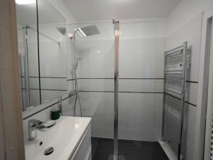 La salle de bains blanche est pourvue d'une douche et d'un lavabo. dans l'établissement Grand F1 - Metro Direct Paris et sites Olympiques, à Issy-les-Moulineaux