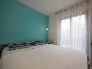 Cet appartement comprend une chambre dotée d'un lit avec un mur bleu et une fenêtre. dans l'établissement Grand F1 - Metro Direct Paris et sites Olympiques, à Issy-les-Moulineaux