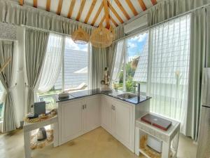 - une cuisine avec des placards blancs et de grandes fenêtres dans l'établissement Piramida's White Villa's Bali - Joglo, à Canggu
