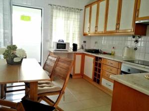 a kitchen with wooden cabinets and a table and a microwave at Marina Mar Vila Franca do Campo in Vila Franca do Campo