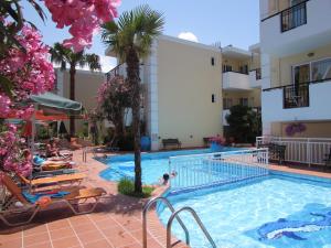 una piscina en un hotel con personas sentadas en sillones en Bueno Hotel en Platanés