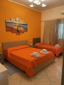 two beds in a bedroom with orange walls at Edeler House in Pula
