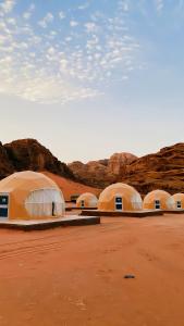 a row of domes in the desert with mountains at Yellow Star Camp Wadi Rum in Wadi Rum