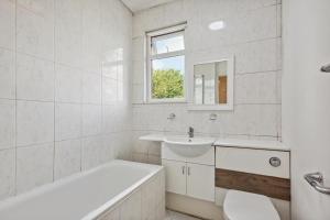 uma casa de banho com um lavatório, uma banheira e um WC. em Cozy Stay Rooms em Raynes Park