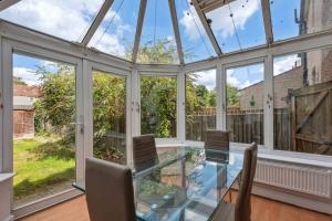 an empty conservatory with a glass table and chairs at Cozy Stay Rooms in Raynes Park