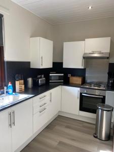 a kitchen with white cabinets and a stove top oven at Welltrees Apartments 10 Dailly Road in Maybole