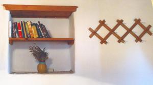 a wall with a shelf and a vase with books at Kaiti’s House in Arkoi