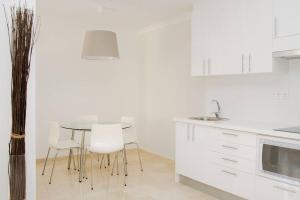 eine weiße Küche mit einem Tisch und weißen Stühlen in der Unterkunft Canary Lofts Rambla in Santa Cruz de Tenerife