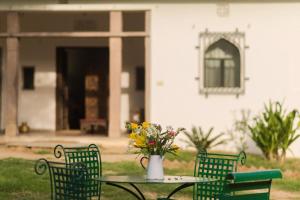 a table and chairs with a vase of flowers on it at Kawa Guest House in Jaipur
