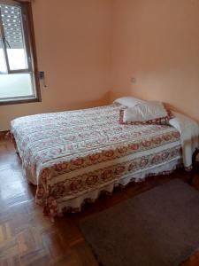 een slaapkamer met een bed met een deken en een raam bij Casa da Fariñeira in Redondela