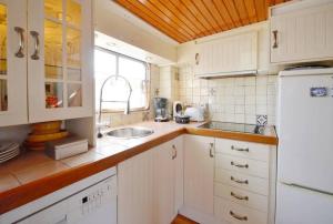 a white kitchen with a sink and a refrigerator at Houseboat Captain's Quarters in Harbour Amsterdam in Amsterdam