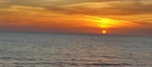 un tramonto sull'oceano con il tramonto di Sencillo apartamento en primera línea de playa a Tavernes de Valldigna
