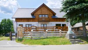 une grande maison en bois avec une clôture devant elle dans l'établissement Całorocznik apartamenty, à Ryczów