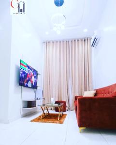 uma sala de estar com um sofá vermelho e uma televisão em FayFays Edifice C1 A Luxury 4 Bedroom Terrace Duplex em Lekki