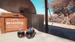 two glasses of wine on a table next to a wooden box at Paso del Campo Estrellado in Humahuaca