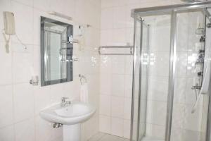 a white bathroom with a sink and a shower at Hotel Karisimbi in Kigali