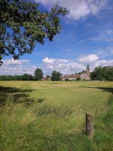 a field of green grass with a church in the background at Le pigeonnier d'Agnès in Jenzat +20 photos