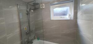 ducha con puerta de cristal y ventana en New Bubble Apartments, en Londres