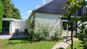a house with a garden and a chair in the yard at huisje Zilvermeeuw in Burgh Haamstede