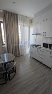 a kitchen with white cabinets and a table and a dining room at Квартира в новом жилом комплексе Invest House in Tashkent