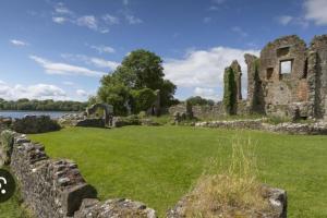 an old ruin of a castle with a green field at Lakeland Lodge in Derrylin