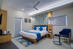 um quarto com uma cama king-size e uma cadeira azul em Cozzet Victoria Hotel em Bhubaneshwar