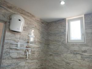 a bathroom with a stone wall and a window at 2-ра двойна стая in Dragoman