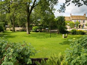 a green yard with trees and a house at Park Grange Cottage in Skipton