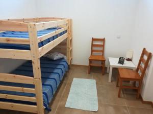 a bedroom with two bunk beds and a table and chair at Pôr do Sol in Aljezur