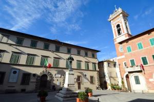 ein Gebäude mit einem Uhrturm und einem Gebäude in der Unterkunft Casa vacanze Fatucchi in Foiano della Chiana