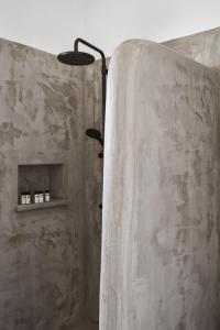 a bathroom with a shower with a wall at Mr & Mrs White Mykonos in Platis Gialos