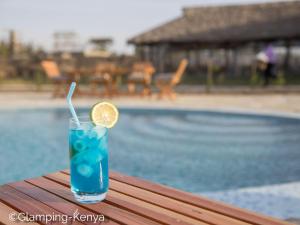 Glamping Kenya Mt. Kenya Lodge في Naro Moru: مشروب أزرق مع شريحة ليمون جالسة على طاولة بجوار حمام سباحة
