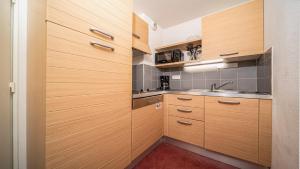 una pequeña cocina con armarios de madera y fregadero en Chalets du Verdon 3302 - pied des pistes -6 pers, en Allos