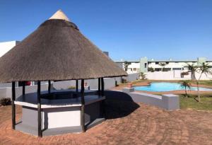 a pavilion with a straw roof next to a pool at Nomads Nook 7 Sea view 6 Sleeper in Margate