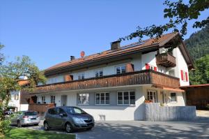 a house with two cars parked in front of it at Gästehaus am Brunnen in Bad Hindelang