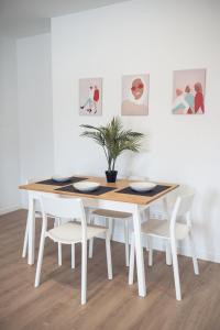 una mesa de comedor blanca y sillas con maceta en ALFALFA A Apartments, en Madrid