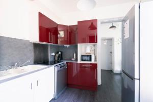 a kitchen with red cabinets and a white sink at La Verrière by la Maison de Marc- Poitiers Centre - parking et terrasse in Poitiers